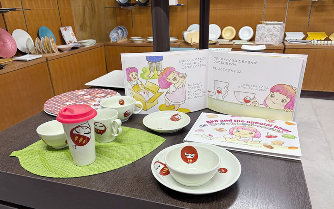 絵本に登場した「だるまくん」の実際の食器と一緒にディスプレイされた絵本