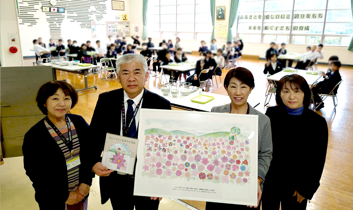 小中学生が描いた花の絵を載せたページを拡大して額装し、絵本と共に学校に寄贈