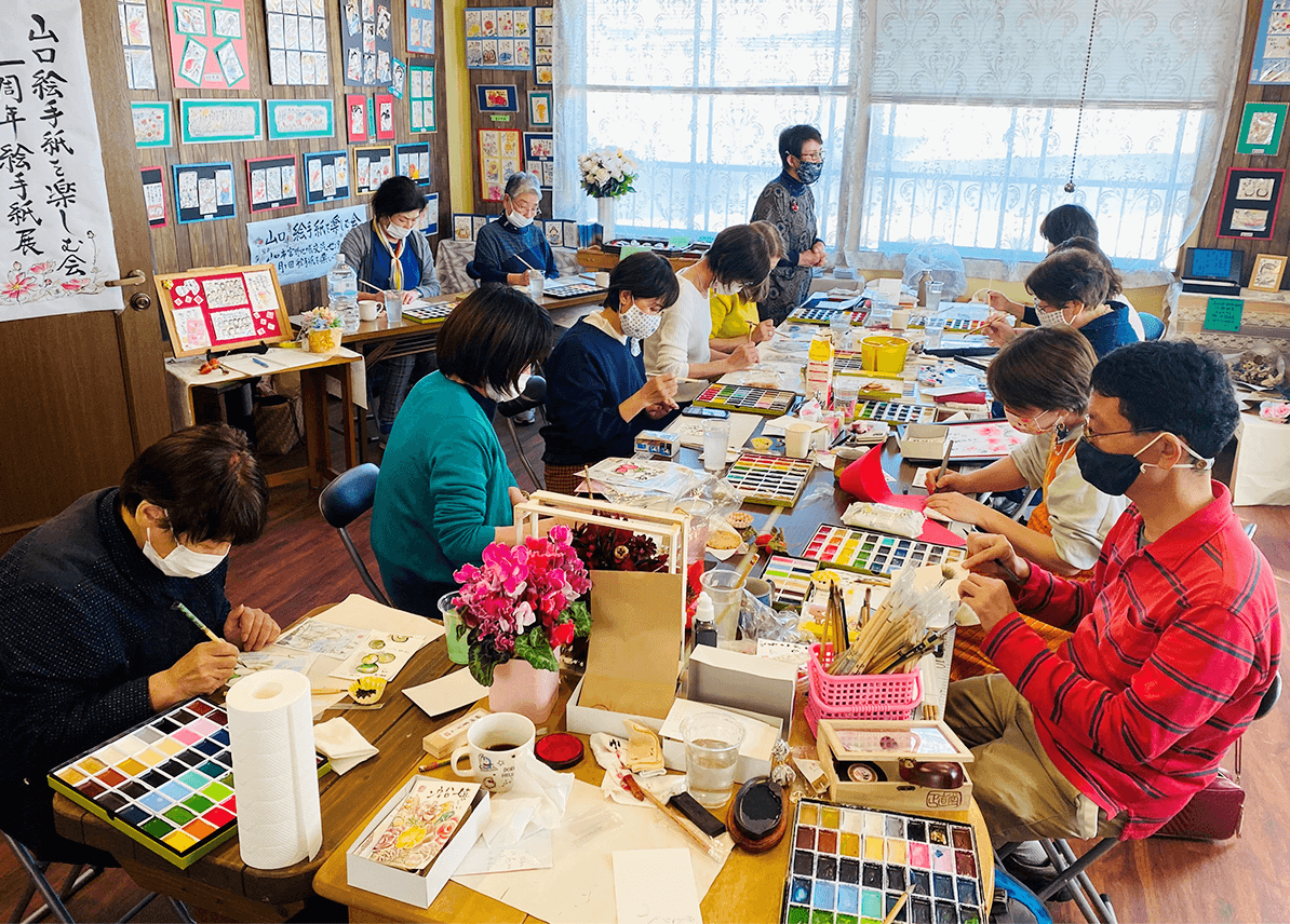 山口県の絵手紙教室でたくさんの生徒さんと絵を描いている様子